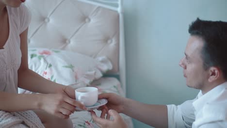 젊은 남자는 아침에 여자에게 커피 한 잔을 주고 웃는 클로즈업 슬로우 모션을 보인다