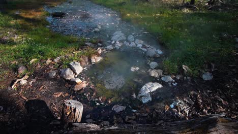 nature hot spring which is bubbling gently among some rocks as steam rises from the water on a late summer evening in pai thailand