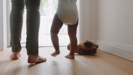 baby learning to walk toddler taking first steps with mother helping infant teaching child at home