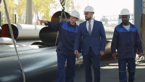 plant workers showing steel pipes to male supervisor