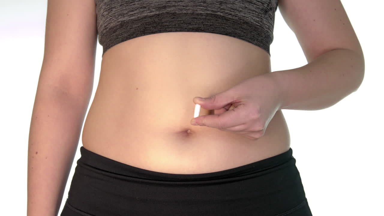 Lassativi. La donna obesa alza la mano con la pillola all'altezza della pancia. La compressa contiene un lassativo. La donna ha problemi di digestione e funzionalità intestinale. Un modo per essere in sovrappeso