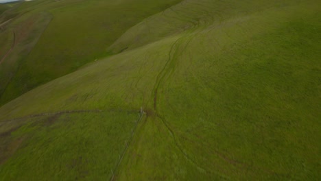 Low-angle-reveal-drone-shot-of-Wind-Turbine-at-Altamont-Pass-on-Vasco-Road-Highway-with-green-rolling-hills-in-California