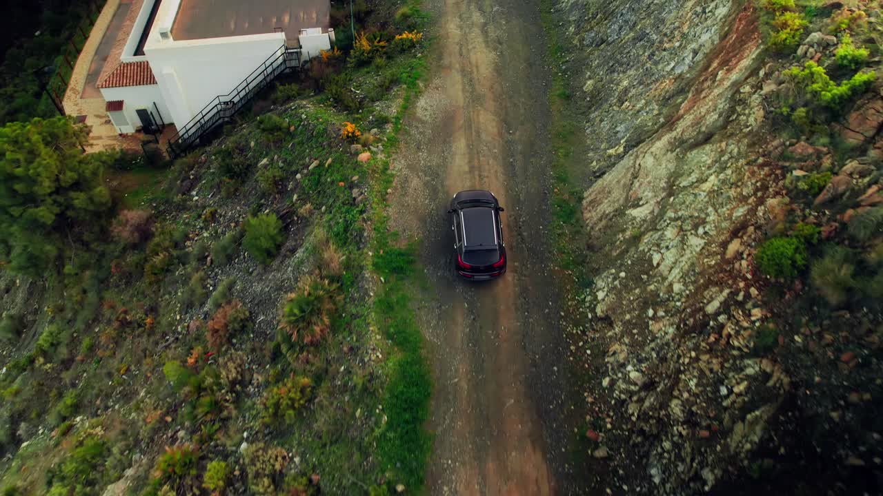 Vista aerea a volo d'uccello di un'auto che guida su una strada sterrata.
