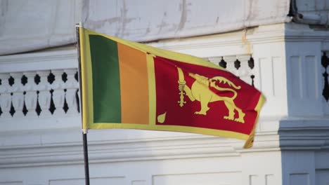 sri lankan national flag waving infront of the rampart hotel and restaurant in galle fort sunset lighting in background, slow motion static b roll clip