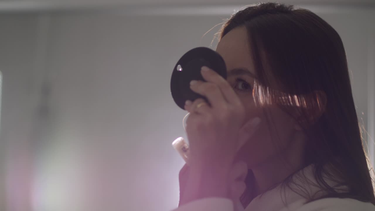 una dama morena se maquilla los ojos con un pequeño espejo iluminado