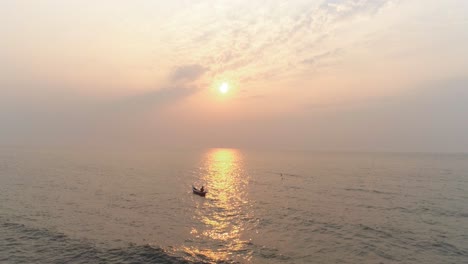 Un-Pescador-En-Un-Bote-Con-La-Puesta-De-Sol-En-La-Parte-Trasera-Captura-Con-Un-Dron-En-El-Mar-Arábigo-Desde-La-Costa-De-Mumbai,-Donde-Se-Avecina-El-Próximo-Proyecto-De-Carretera-Costera