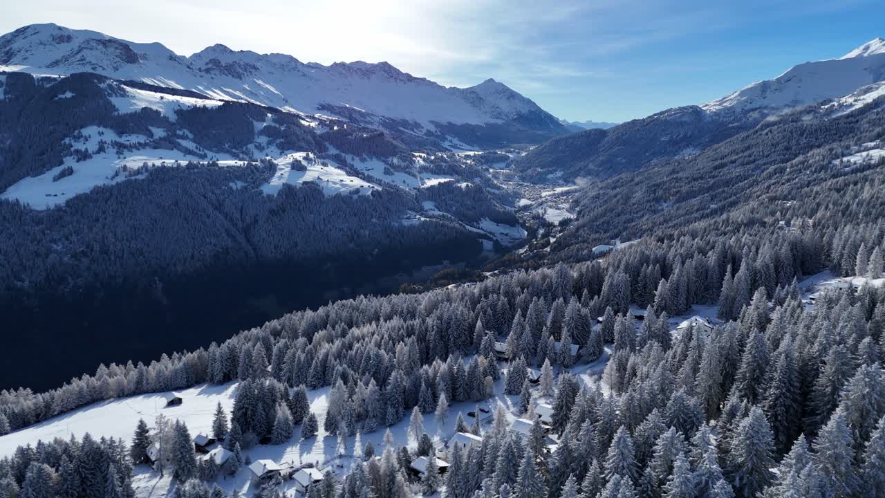 Luftaufnahme von verschneiten Bergen und Waldlandschaft mit dem Dorf Brambrüesch im Tal, Chur, Schweiz – Panoramablick