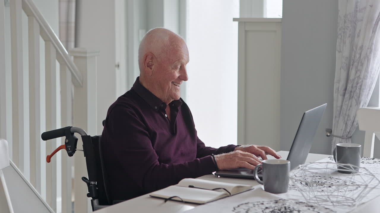 Senior man in wheelchair using laptop at home