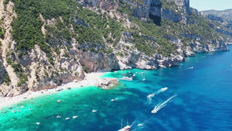 excursiones en barco y turistas en la playa de cala mariolu, costa de baunei, cerdeña, italia - antena 4k
