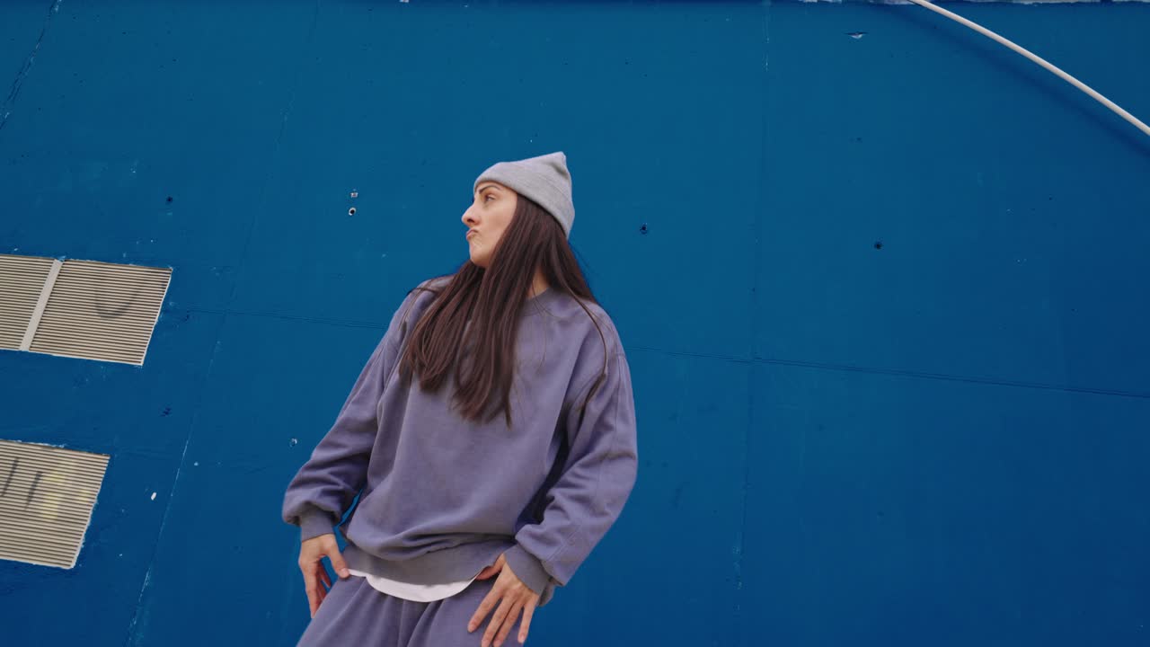 Woman dancing in front of a blue wall