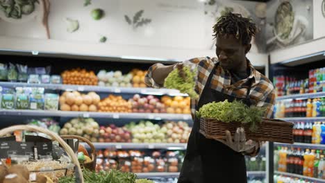 african american worker arranging greens in the supermarket