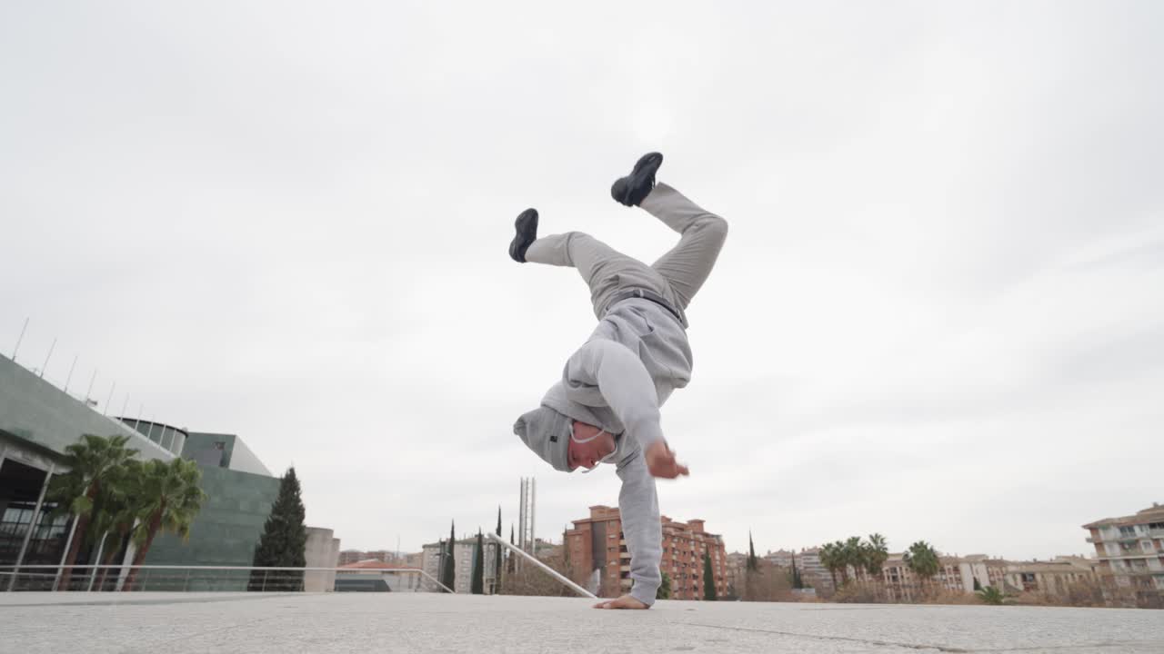 Breakdancer performing handstand in urban setting