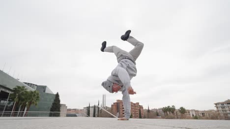 breakdancer performing handstand in urban setting