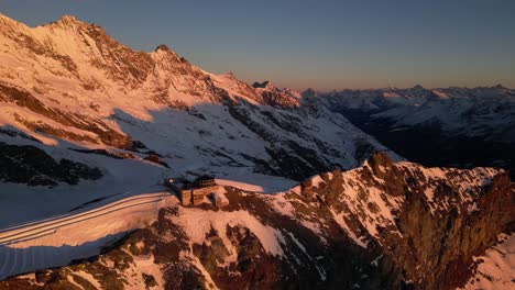 aerial view of a building on top of the alps, on a mountain ridge during a sunrise