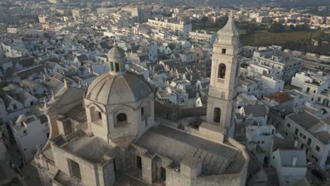drone volando sobre la ciudad medieval locorotondo revela la cúpula y la torre de la chiesa madre di san giorgio martire