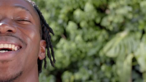 medio retrato de un feliz hombre afroamericano con espacio de copia en el jardín soleado, cámara lenta