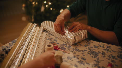 hombre envolviendo papel de regalo en una caja en la mesa