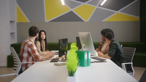 multinational people sit at desks working on computers