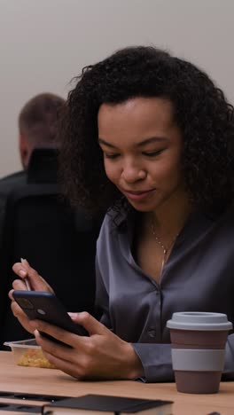 businesswoman eating lunch and using smartphone in office meeting