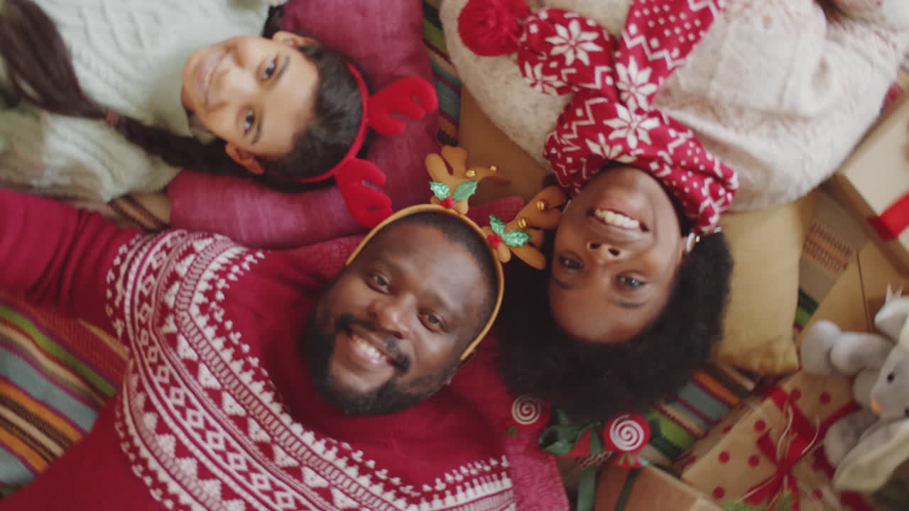 familia afroamericana tendida en el suelo y sonriendo a la cámara en navidad