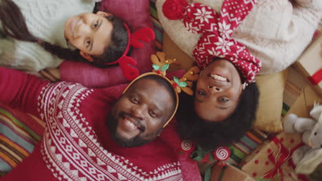 african american family lying on floor and smiling at camera on christmas