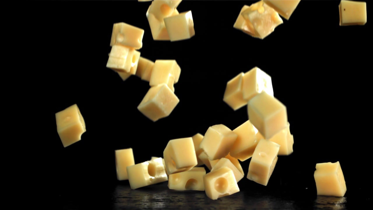 Cubes de fromage tombant au ralenti sur fond noir