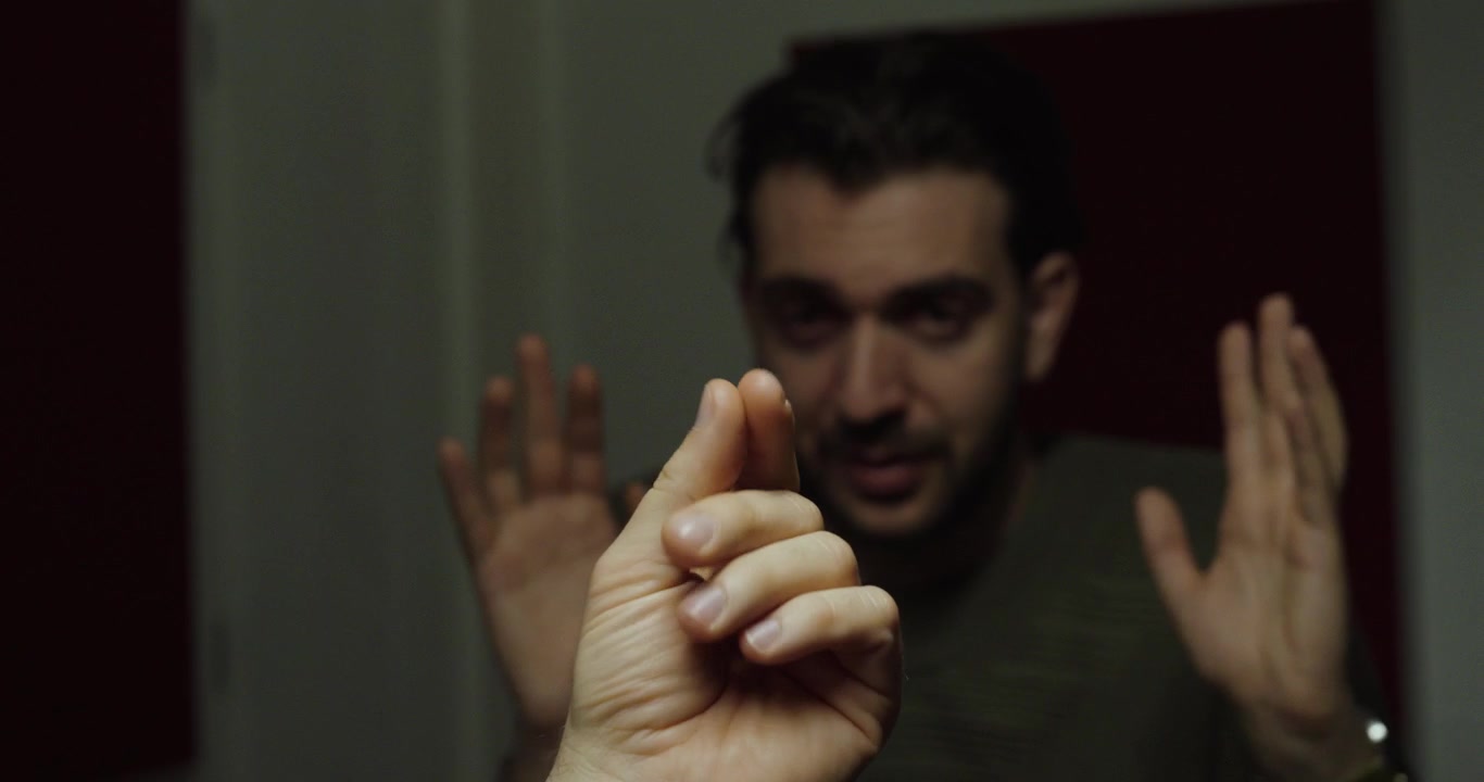Person making a hand gesture indicating a demand for money during a tense interpersonal confrontation.