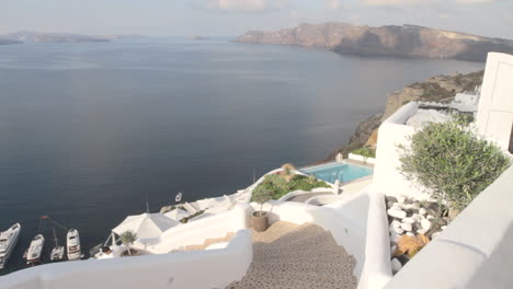 a man is rushing down some open air stairs in a village alley at the greek village of oia in santorini