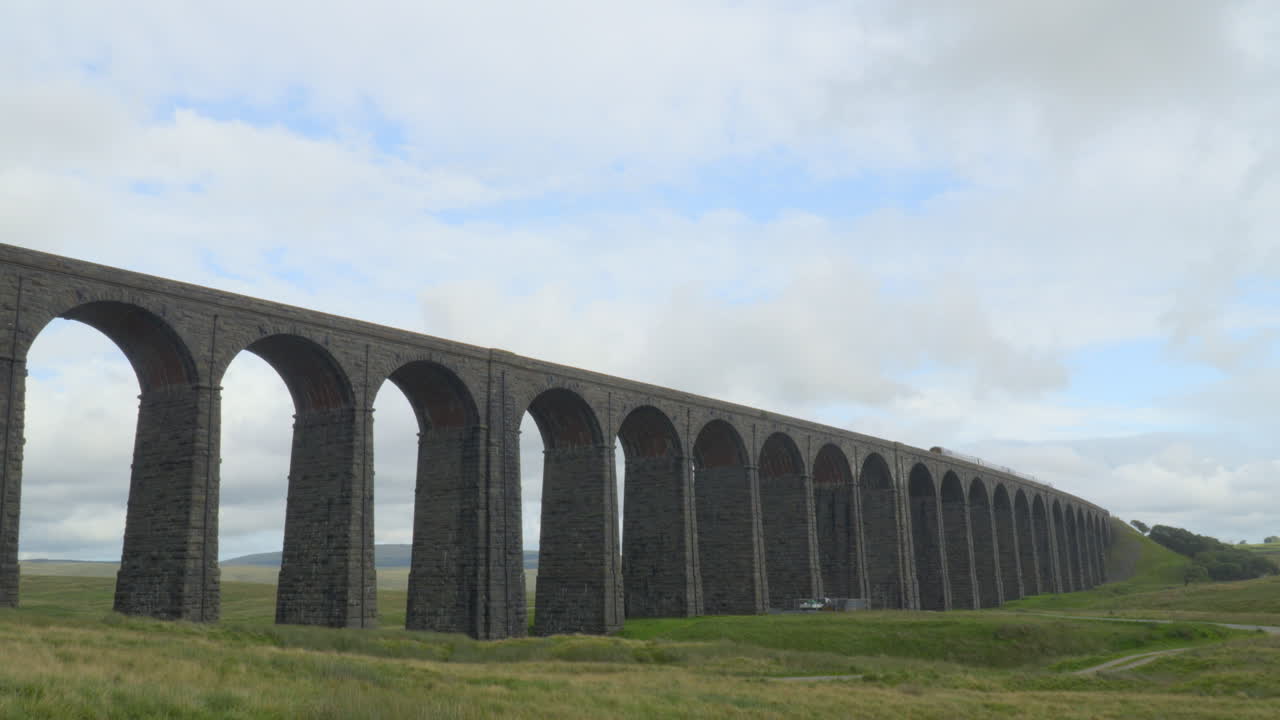 리블헤드 다이아 ⁇ , 요크셔, 영국 에서 지나가는 열차 와 함께 바람이 부는 구름진 여름 오후 에 무어랜드 를 가로지르는 다리