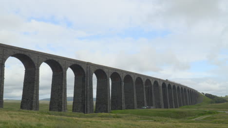 viaduct bridge over moorland on windy overcast summer afternoon with passing train at ribblehead viaduct, yorkshire, uk