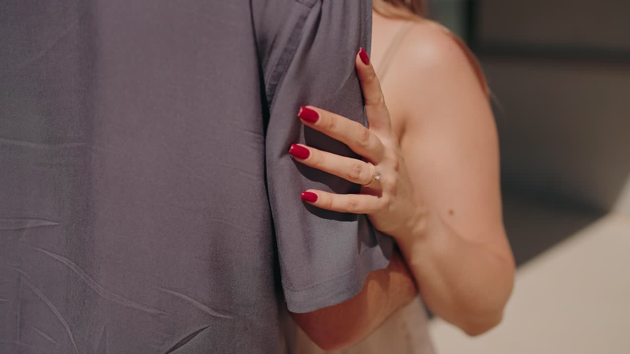 Close up of a woman embracing a partner showing red nails and affection