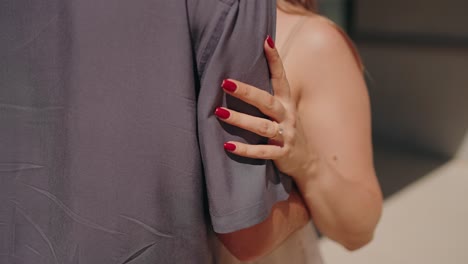 close up of a woman embracing a partner showing red nails and affection