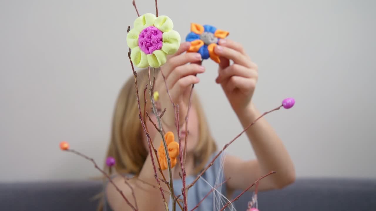Bambina che decora rami con fiori fatti a mano per la primavera