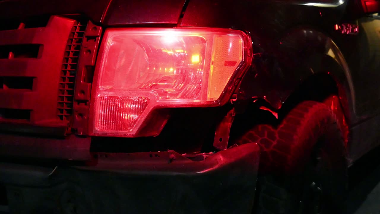 police light flashing on a damaged pickup truck wheel well after a wreck