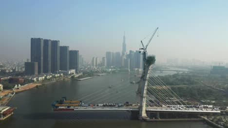 drone view of saigon river, ho chi minh city and new thu thiem bridge under construction on a sunny day