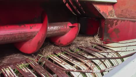 A-view-of-the-front-of-an-old-square-baler-showing-the-pickup,-feed-auger-and-fingers