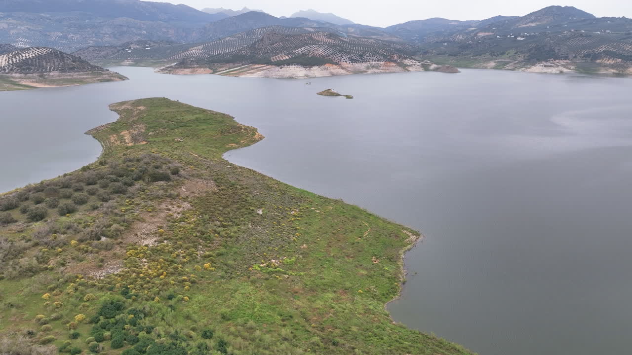 Autumnal flight over lush island olive groves and headland Iznajar reservoir