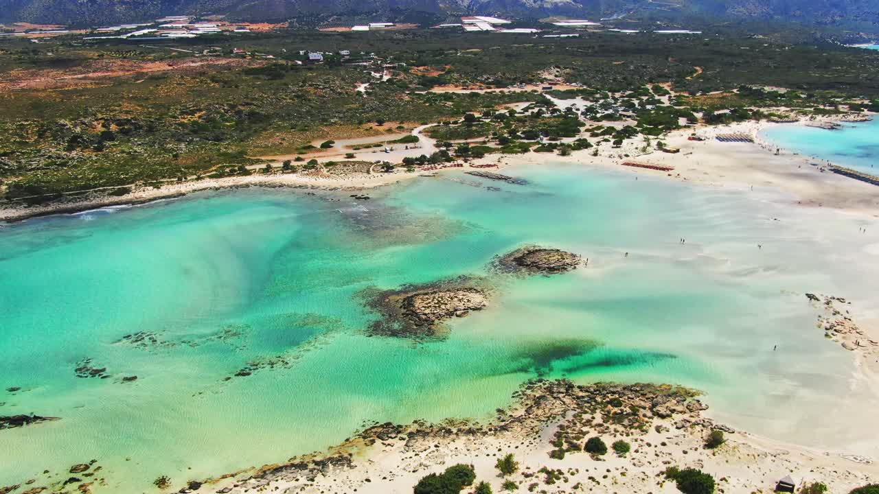 Aerial of Elafonisi lagoon, Crete, Greece showing the spectacular view of pink sand beaches surrounded by mountains. Birds eye view