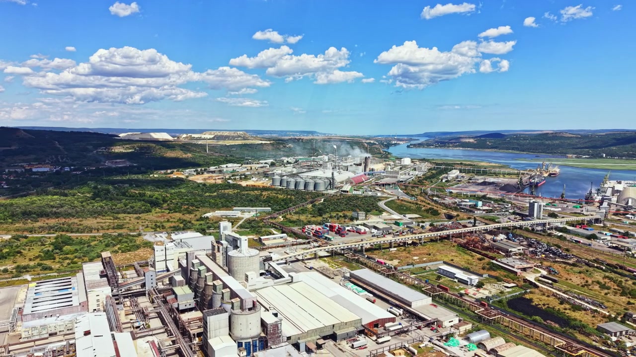 Industrial site near a river with storage silos and factories observed from above on a clear day