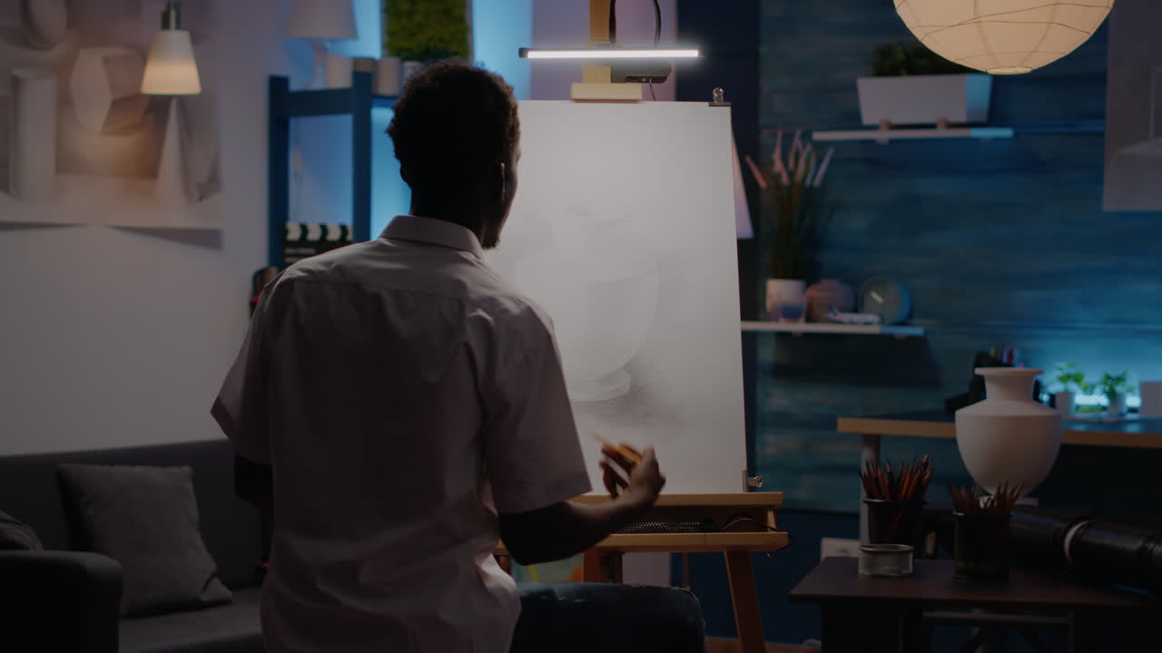 Artist of african american ethnicity using vase for drawing inspiration