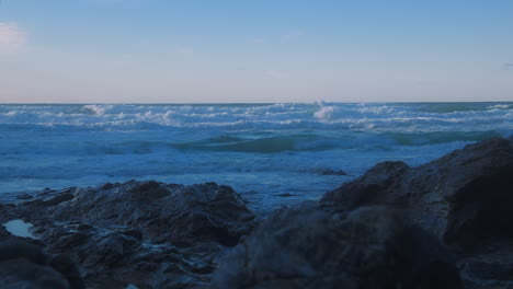 Parallax-view-toward-choppy-ocean-horizon-from-rocky-shore-at-Chapel-Porth,-UK