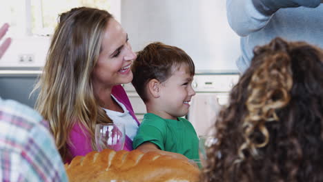 grandfather serving food as multi-generation family meet for meal at home