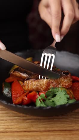 mujer comiendo pescado a la parrilla con verduras