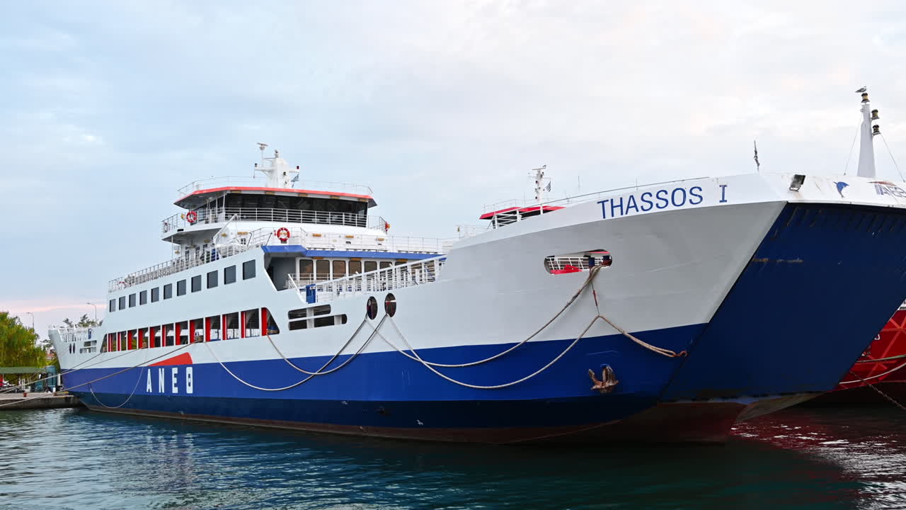 THASSOS, GREECE - SEPTEMBER 23, 2020: Moored ferryboats in the port with red and blue exteriors, opened. Cloudy weather