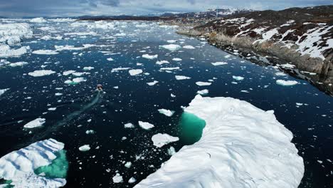 Lonely-boat-in-deep-ocean-near-icebergs,-aerial-drone-view