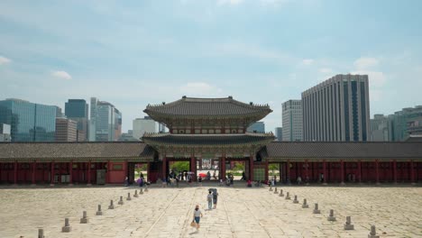 Geunjeongmun-Tor-Des-Gyeongbokgung-Palastes-Mit-Touristen,-Die-An-Einem-Sommertag-Den-Geunjeongjeon-Hallenblock-Vor-Bürogebäuden-In-Seoul-Betreten