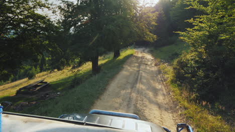 riding an off-road vehicle on an extremely bad road through the forest the setting sun shines throug