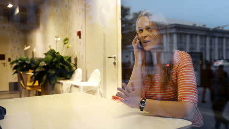 Evening-phone-talk-of-a-young-woman-in-cafe