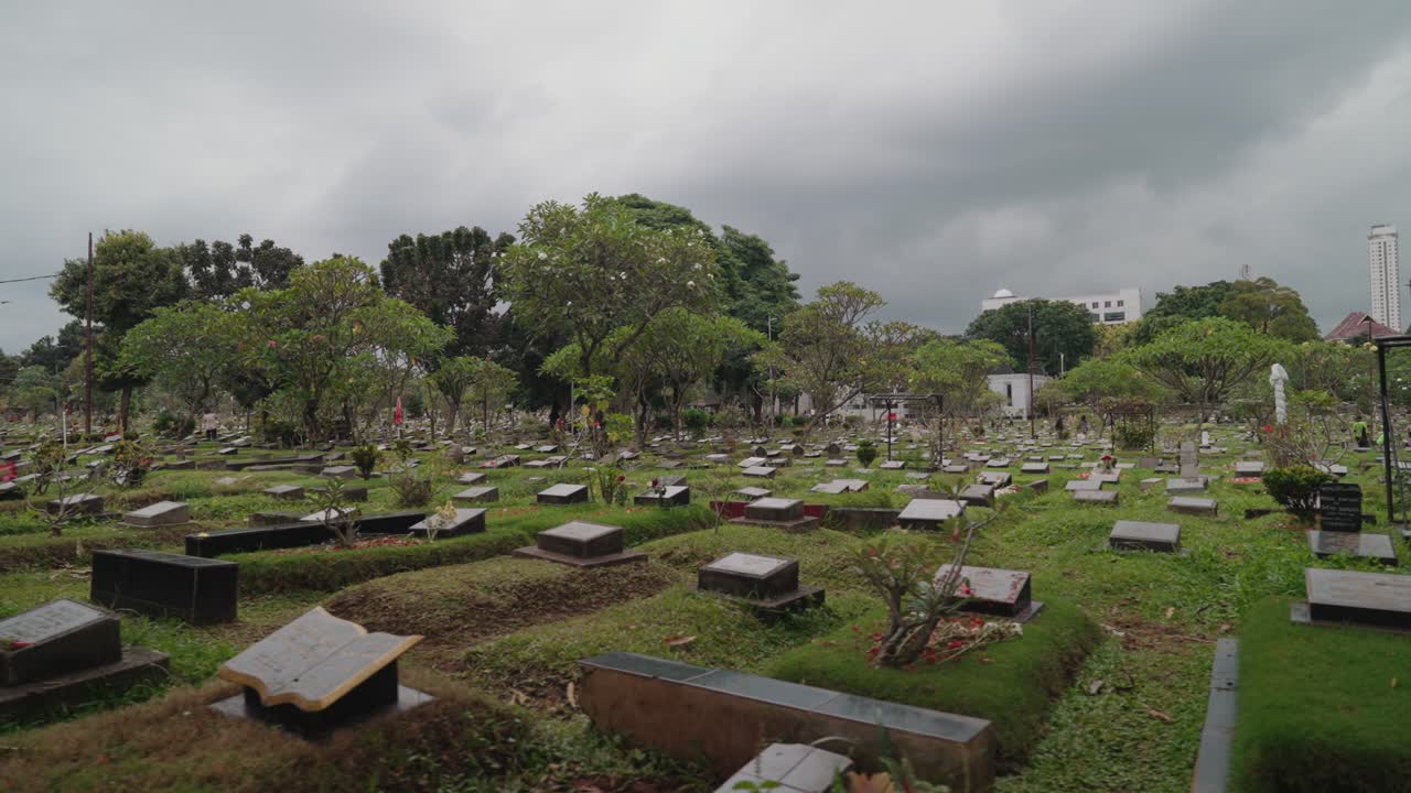 Cimitero tranquillo con tombe verdi e alberi in una giornata nuvolosa