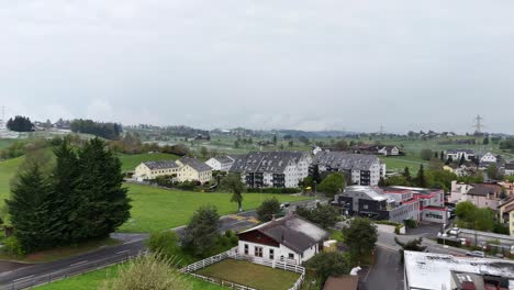 Traffic-on-road-in-small-swiss-town-during-grey-sky-with-snow-on-roofs